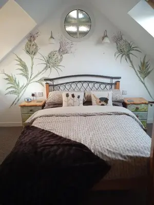 a bedroom with a bed with a cat laying on it at Laurieknowe Coach House in Dumfries
