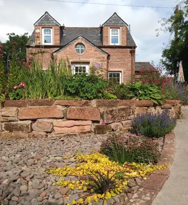 a stone retaining wall in front of a house at Laurieknowe Coach House in Dumfries