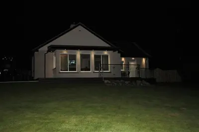 a small white house at night with lights on it at Firpoint in Rockcliffe