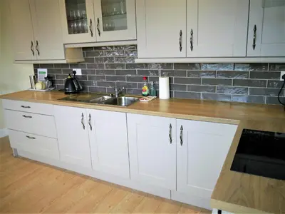 a kitchen with white cabinets and a sink at Firpoint in Rockcliffe