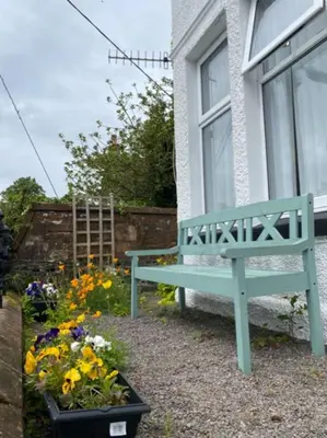 a blue bench in front of a window with flowers at St John's Flat Spacious Accomodation in Dalry