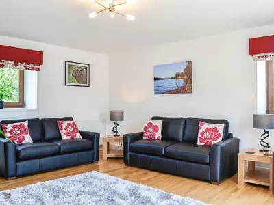 a living room with two black leather couches at The Byre - Camp Douglas - Cottage in Crossmichael