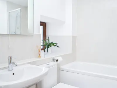 a white bathroom with a sink and a toilet at The Byre - Camp Douglas - Cottage in Crossmichael