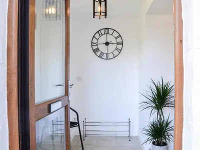 a hallway with a clock on a white wall at The Byre - Camp Douglas - Cottage in Crossmichael