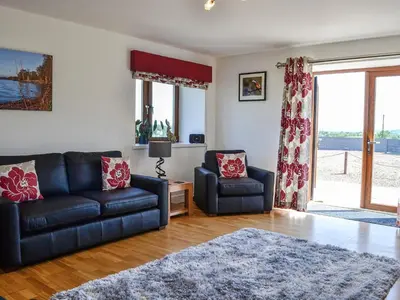 a living room with a couch and a chair at The Byre - Camp Douglas - Cottage in Crossmichael