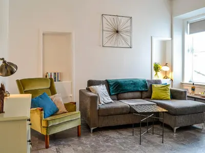 a living room with a couch and a chair at Park Crescent - Cottage in Creetown