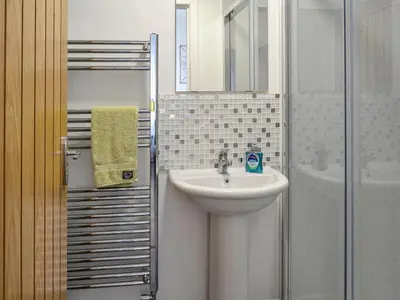 a bathroom with a sink and a mirror and a shower at Park Crescent - Cottage in Creetown