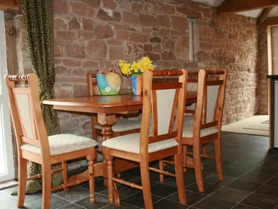a wooden table with two chairs and a table with flowers on it at The Bird Bath - Cottage in Wreay