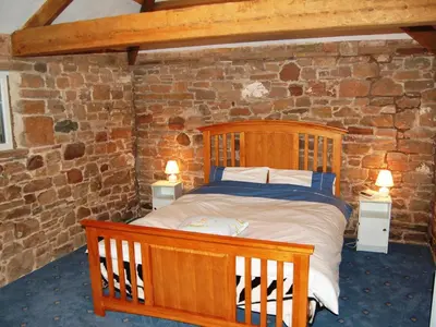 a bedroom with a wooden bed in a brick wall at The Bird Bath - Cottage in Wreay