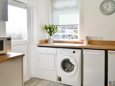 a kitchen with a washing machine and a window at Cardoness Houses in Dumfries