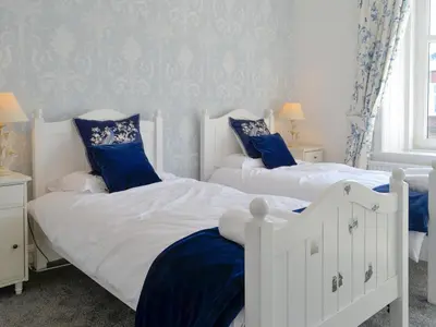 two beds in a bedroom with blue and white at Cardoness Houses in Dumfries