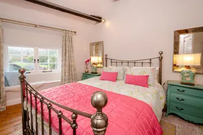 a bedroom with a large bed with pink pillows at Bank View in Chapel Stile