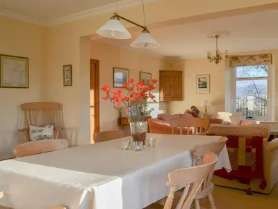 a dining room table with a vase of flowers on it at Middle Howe in Portinscale