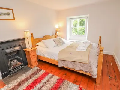 a bedroom with a bed next to a fireplace at Fir Tree Cottage in Ambleside