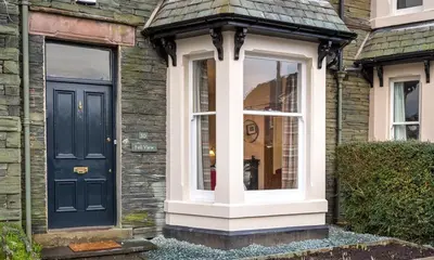 a house with a black door and a window at Thirty Blencathra Street in Keswick