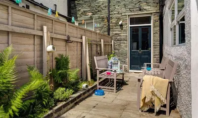 a patio with two chairs and a table and a building at Thirty Blencathra Street in Keswick