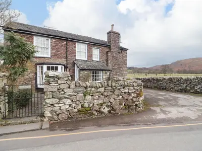 an old stone house with a stone wall at Pavement End Cottage in Grasmere