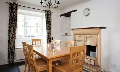 a dining room with a wooden table and chairs at Pollys Cottage in Elterwater
