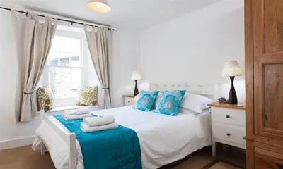 a bedroom with a white bed with blue pillows at Pollys Cottage in Elterwater