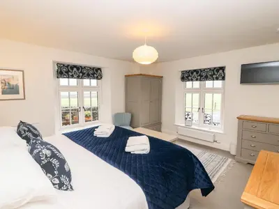 a bedroom with two beds and two windows at Tilly's Cottage in Grasmere