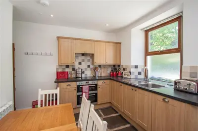 a kitchen with wooden cabinets and a table and a window at Robins Nest in Coniston