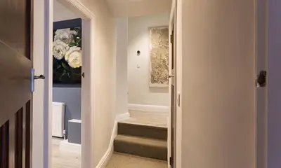a hallway with stairs and a painting on the wall at Riverville in Grasmere