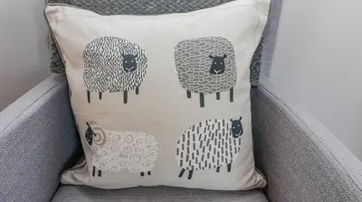 a pillow with four sheep on a chair at Bowderstone in Keswick