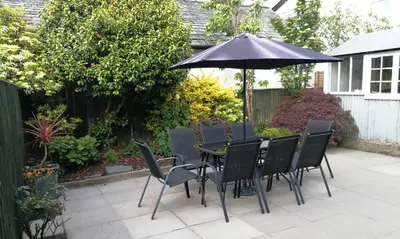 a patio with a table and chairs and an umbrella at Bowderstone in Keswick