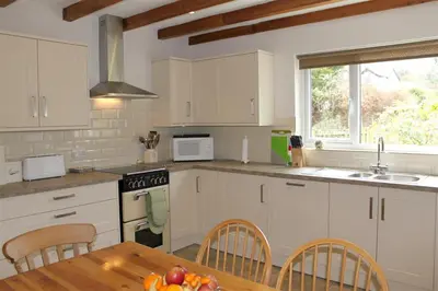 a kitchen with white cabinets and a table with fruit on it at Bandol in Braithwaite