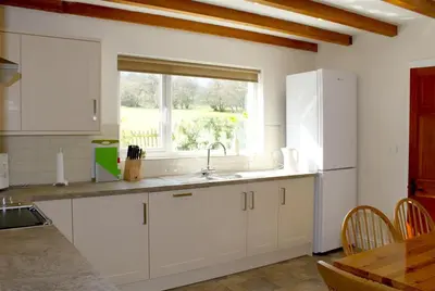 a kitchen with white cabinets and a sink and a window at Bandol in Braithwaite