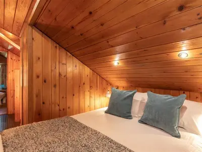 a bedroom with a bed in a wooden wall at Dovecot Cottage in Ambleside