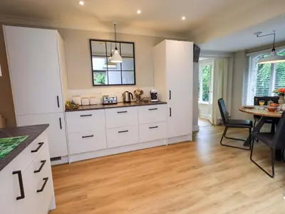 a kitchen with white cabinets and a table and a dining room at Underheron in Grasmere