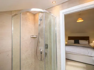 a bathroom with a shower with a bed in the background at Rowanberry Cottage in Grasmere