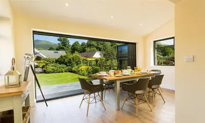 a dining room with a table and chairs and a large window at Greengarth in Keswick