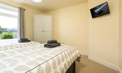 a bedroom with a bed with two chairs and a window at Greengarth in Keswick