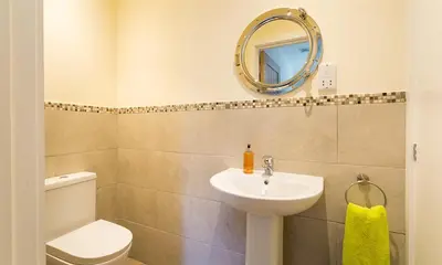 a bathroom with a sink and a toilet and a mirror at Greengarth in Keswick