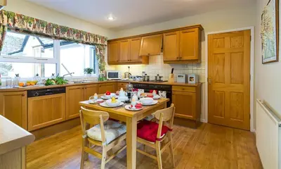 a kitchen with a wooden table and chairs and a kitchen with a window at Felldale in Glenridding