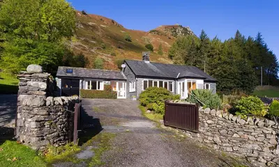 a house with a stone fence and a stone wall at Felldale in Glenridding