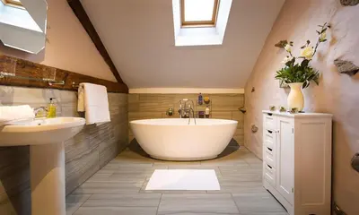 a bathroom with a large tub and a sink at Scalegill House in Cockermouth