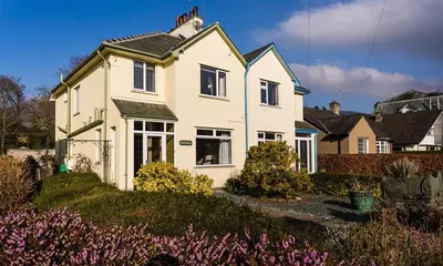 a white house with flowers in front of it at Heathfield in Keswick