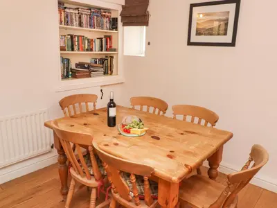 a dining room table with a bottle of wine and a bowl of food at Weir Cottage in Ambleside