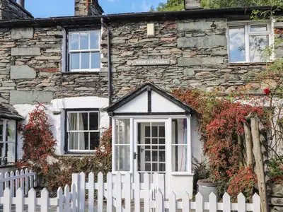 a white fence in front of a stone house at Weir Cottage in Ambleside
