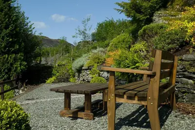 a wooden bench sitting on the ground near a garden at White Lion Cottage in Chapel Stile