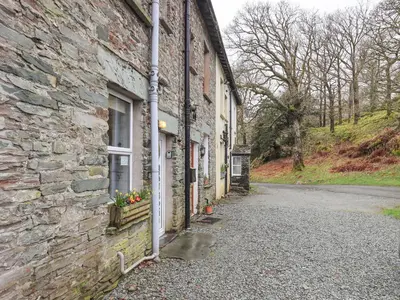 a stone building with a window on a street at Holme Ground Cottage in Coniston