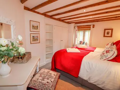 a bedroom with a red bed and a table and a window at Glen View Cottage in Ambleside
