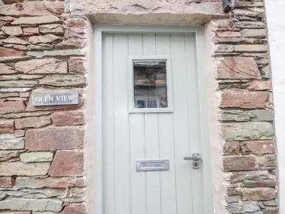 a white door in a stone building with a window at Glen View Cottage in Ambleside