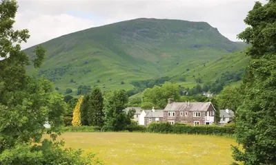 a house in a field in front of a mountain at Glen View Cottage in Ambleside