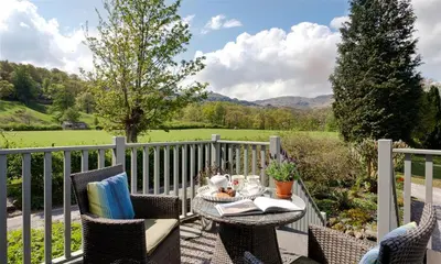 a patio with a table and chairs on a balcony at Glen View Cottage in Ambleside
