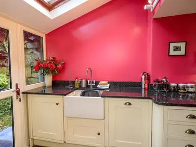 a kitchen with a sink and a red wall at Beck Steps in Chapel Stile
