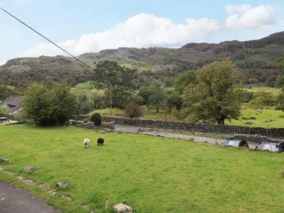 two sheep grazing in a field with mountains in the background at Beck Steps in Chapel Stile